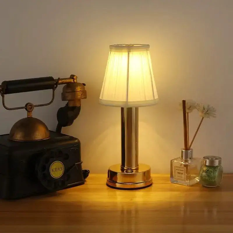 Tania | Lampe Ambiance Au Design Scandinave sur une table avec une lampe allumée, une boîte vintage et des accessoires décoratifs.